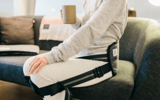 BetterBack worn by person sitting on sofa holding a mug