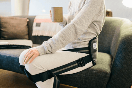 BetterBack worn by person sitting on sofa holding a mug
