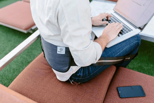 BetterBack worn by person sitting on couch with laptop