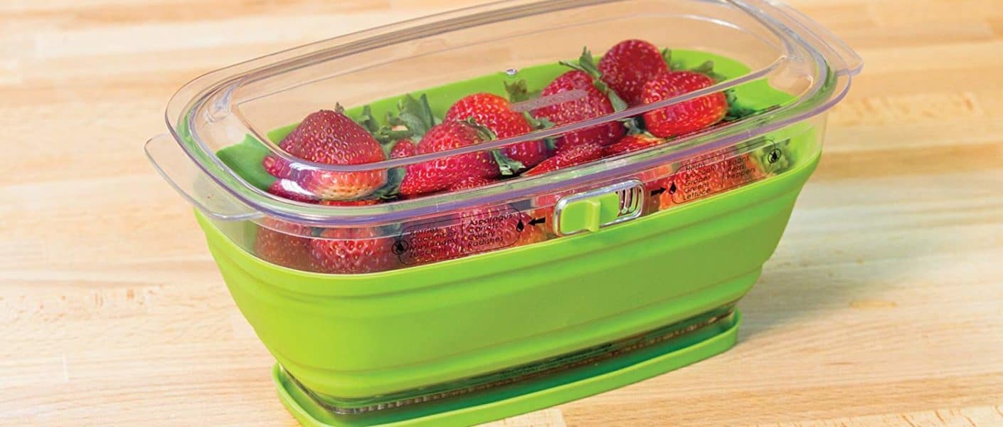 Progressive Prepworks produce keeper in green open on table filled with strawberries