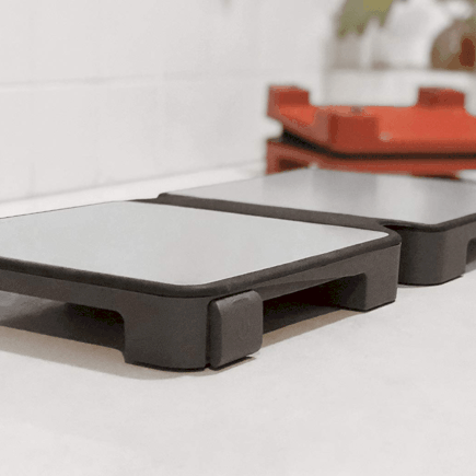 HotMat Hot Plate in grey open on counter in foreground with red folded in background