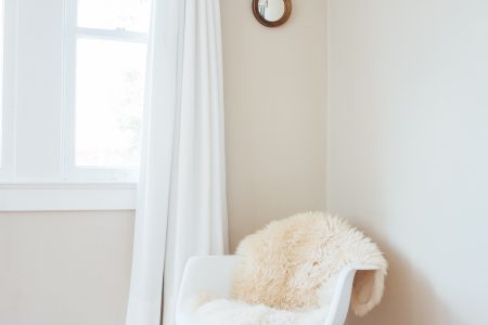 white nursery with daylight in window and white rocking chair